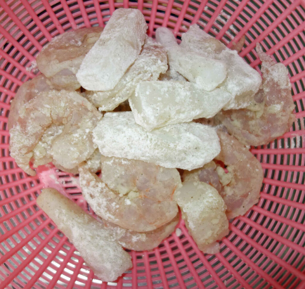ピンクのかごに入った片栗粉をまぶしたエビとレンコン
