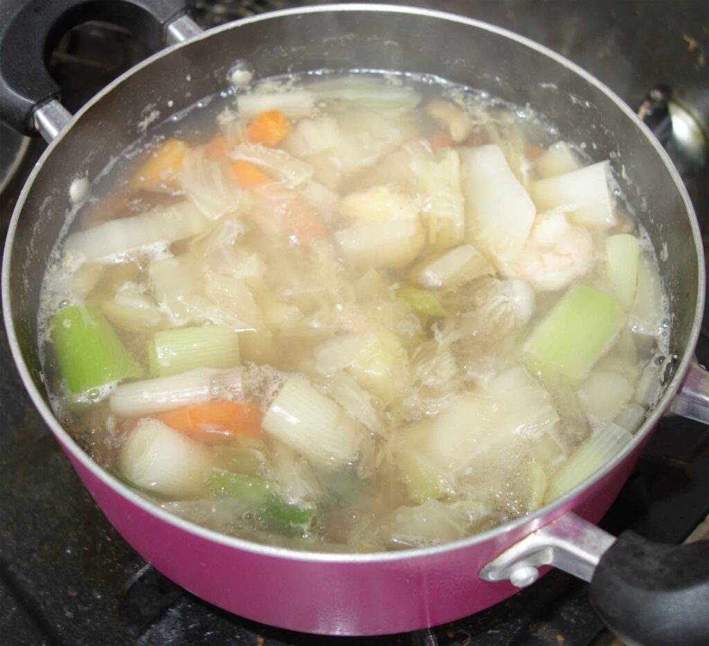 鍋で煮込まれているエビと野菜