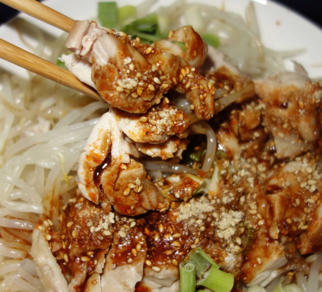 箸で鶏肉をつまみ上げたサラダ