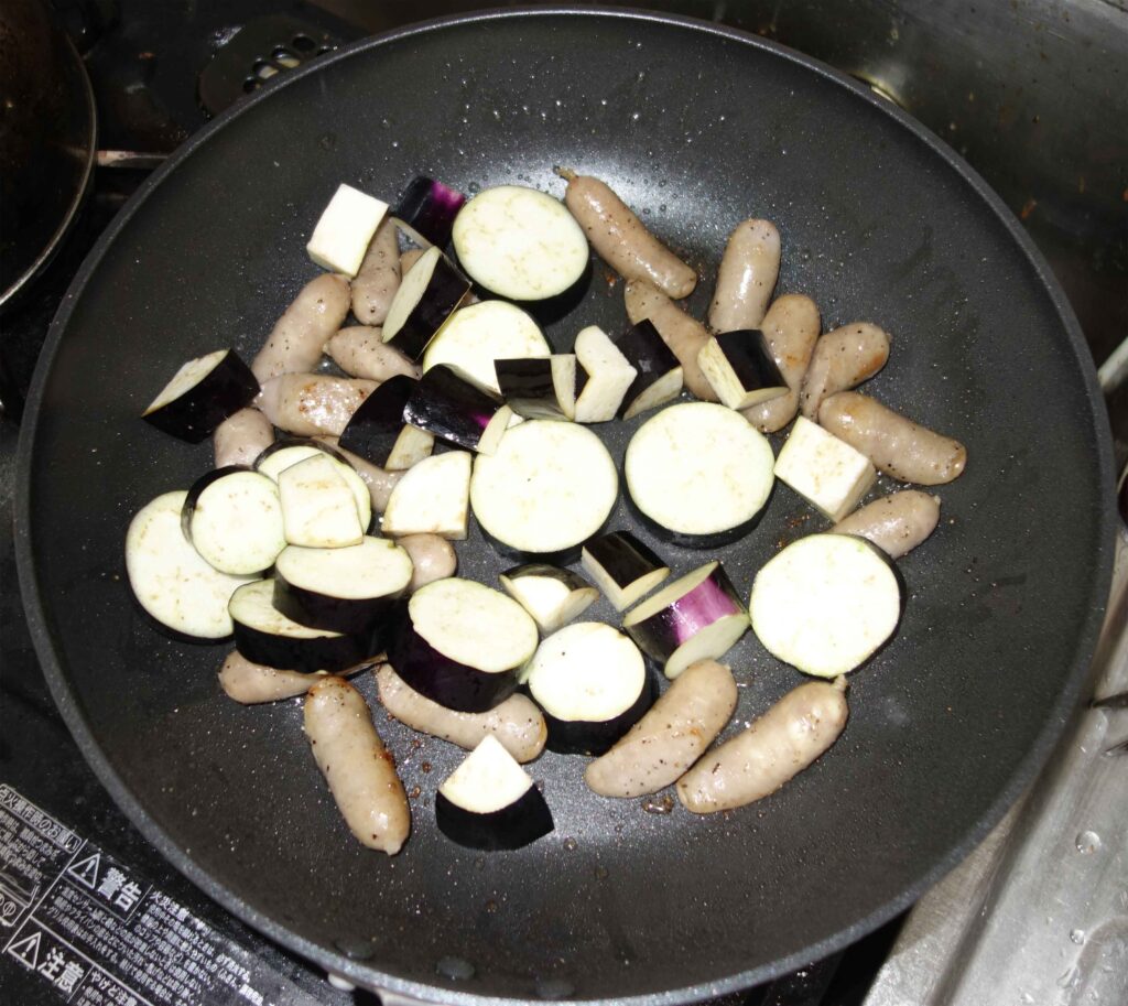 フライパンで炒めているナスとソーセージと豆腐