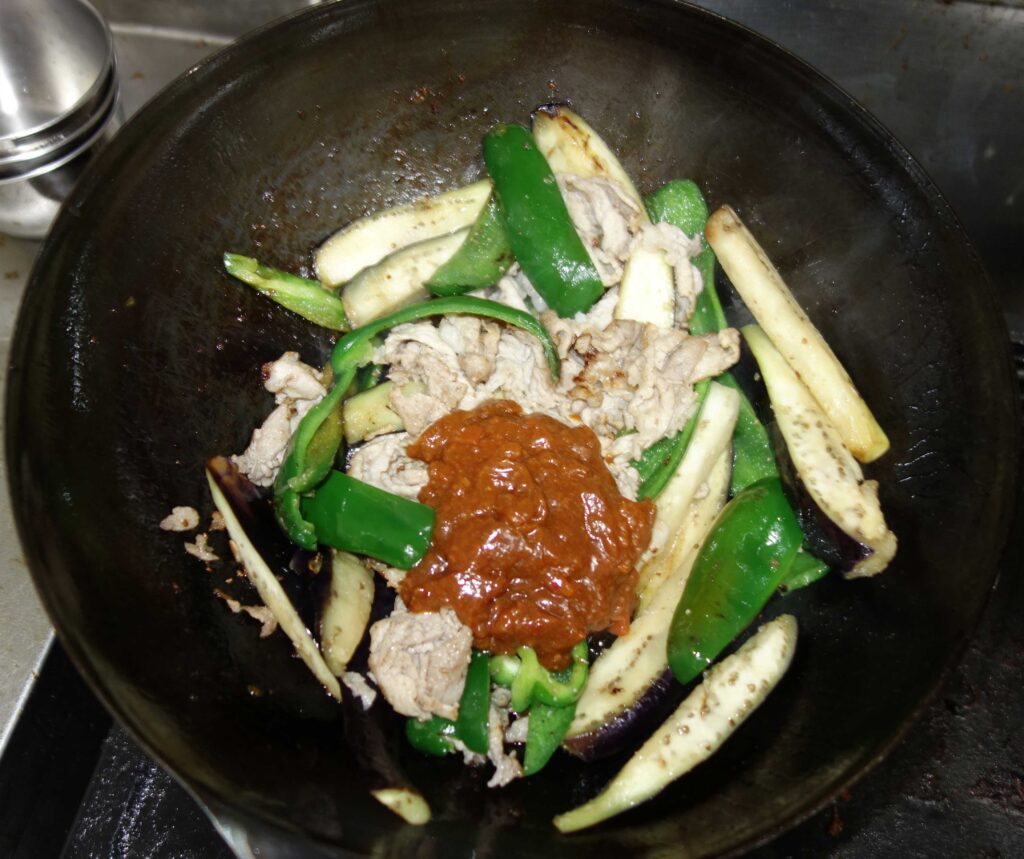 中華鍋で炒められたナスとピーマンと豚肉味噌炒め