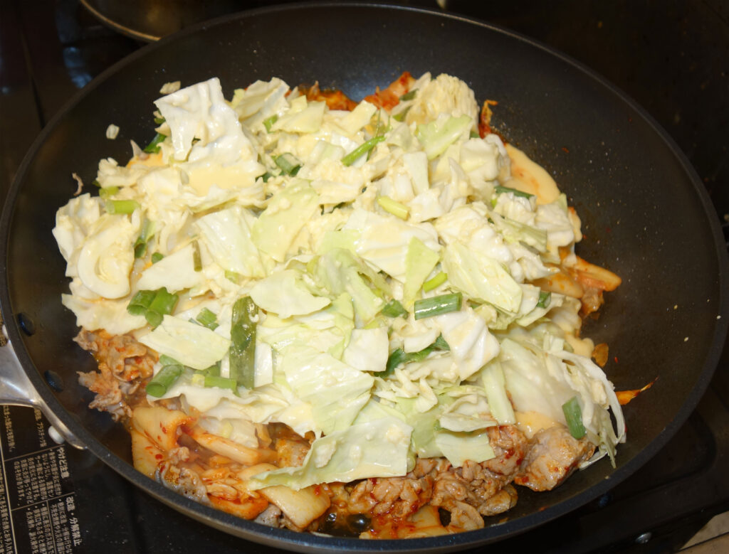 フライパンで調理中の豚キムチとキャベツ