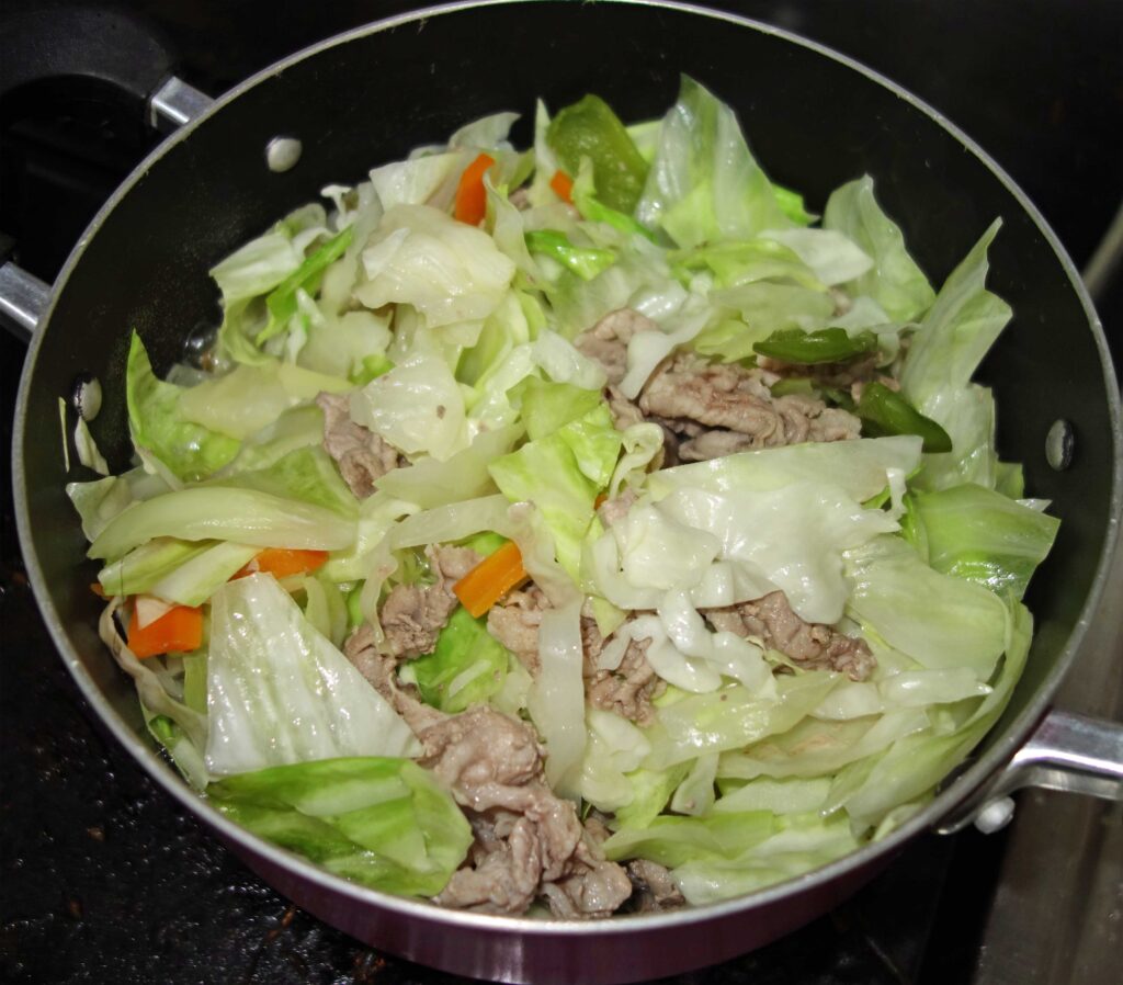 鍋で調理された豚肉とキャベツの炒め物