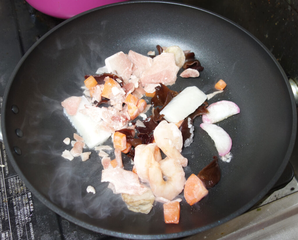冷凍されたエビや肉、野菜などを炒めている様子