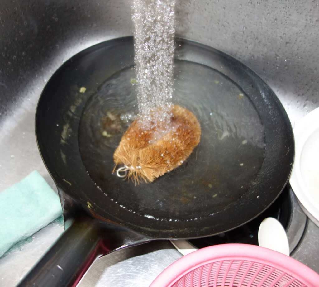 フライパンをタワシで洗う様子