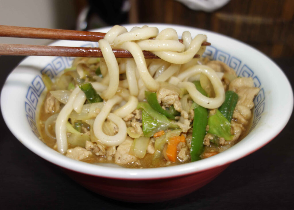 箸で持ち上げられた熱々のカレーうどん