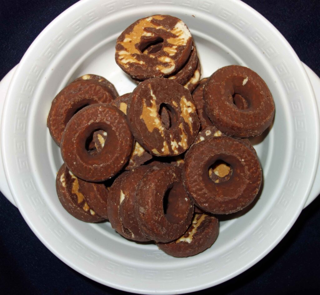 チョコレートでコーティングされたドーナツ型のクッキーを白い器に盛った写真