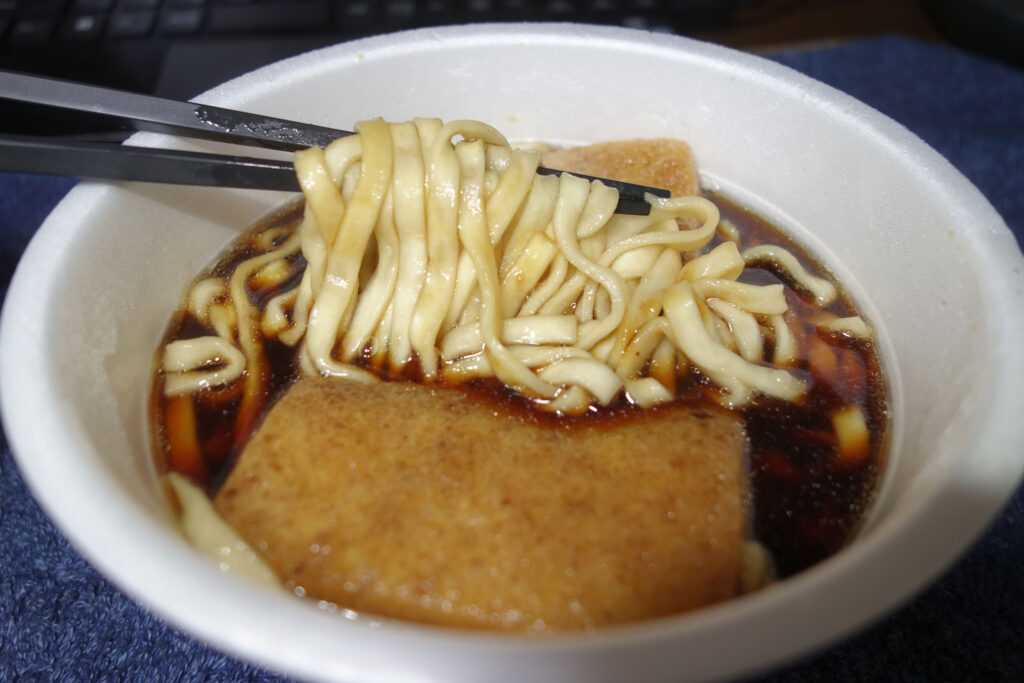 丼に入ったきつねうどんを箸で持ち上げている様子