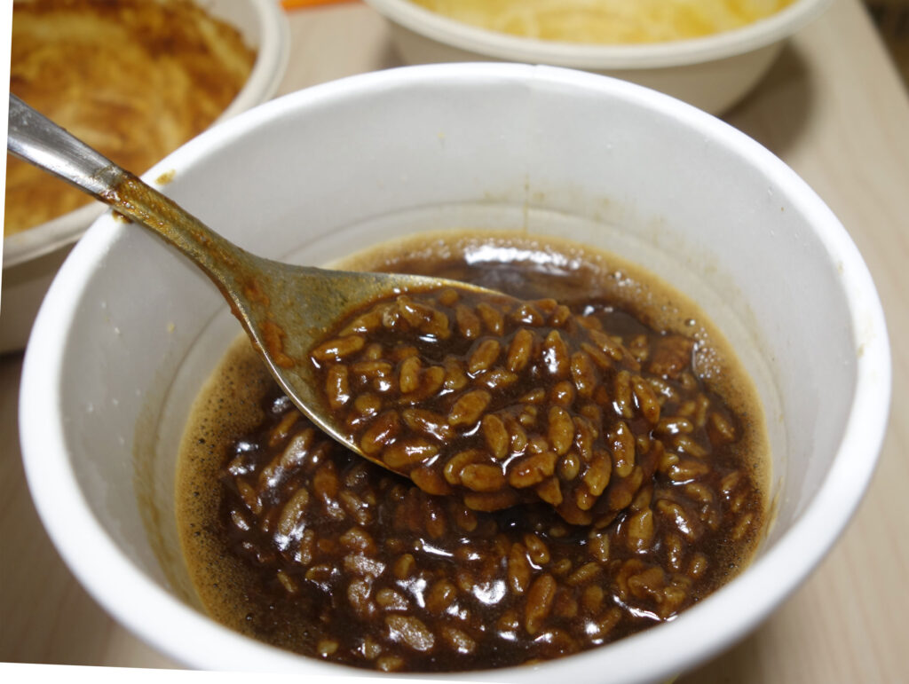 カップに入ったカレーメシをスプーンですくって実食している様子