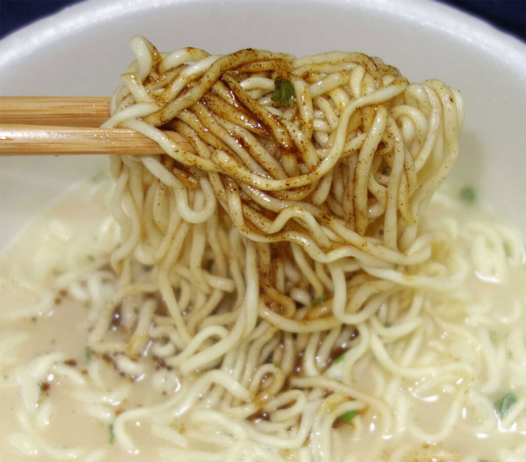 箸で持ち上げられたソースがかかった麺のクローズアップ