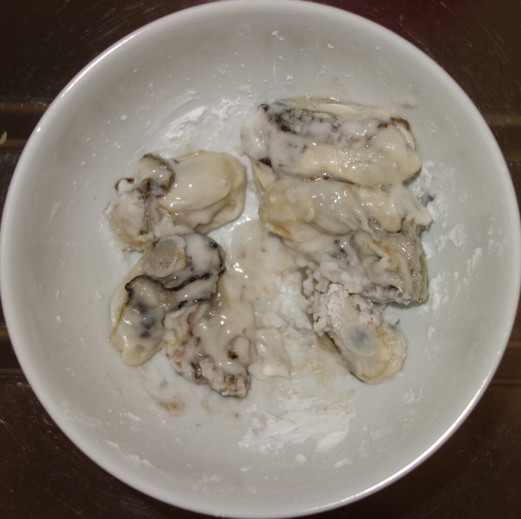 白い器に入った片栗粉をまぶしたカキ