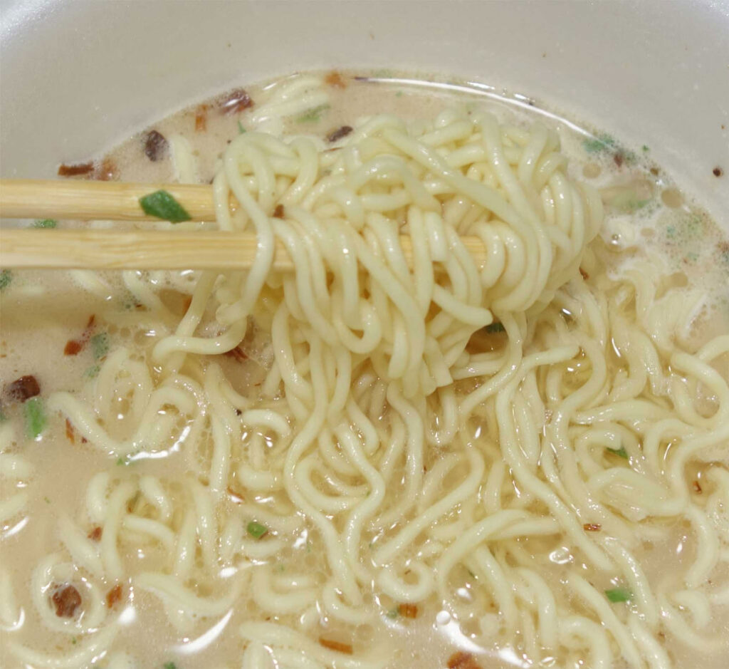 箸で持ち上げられたカップラーメンの麺