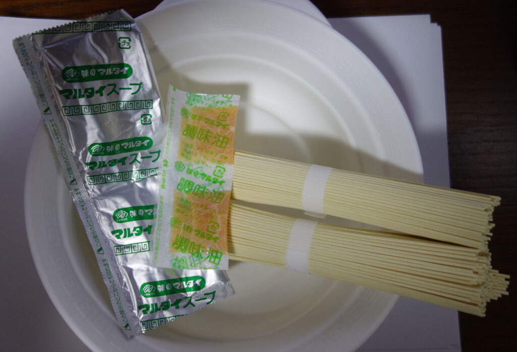 白い丼に入った棒ラーメンとスープ