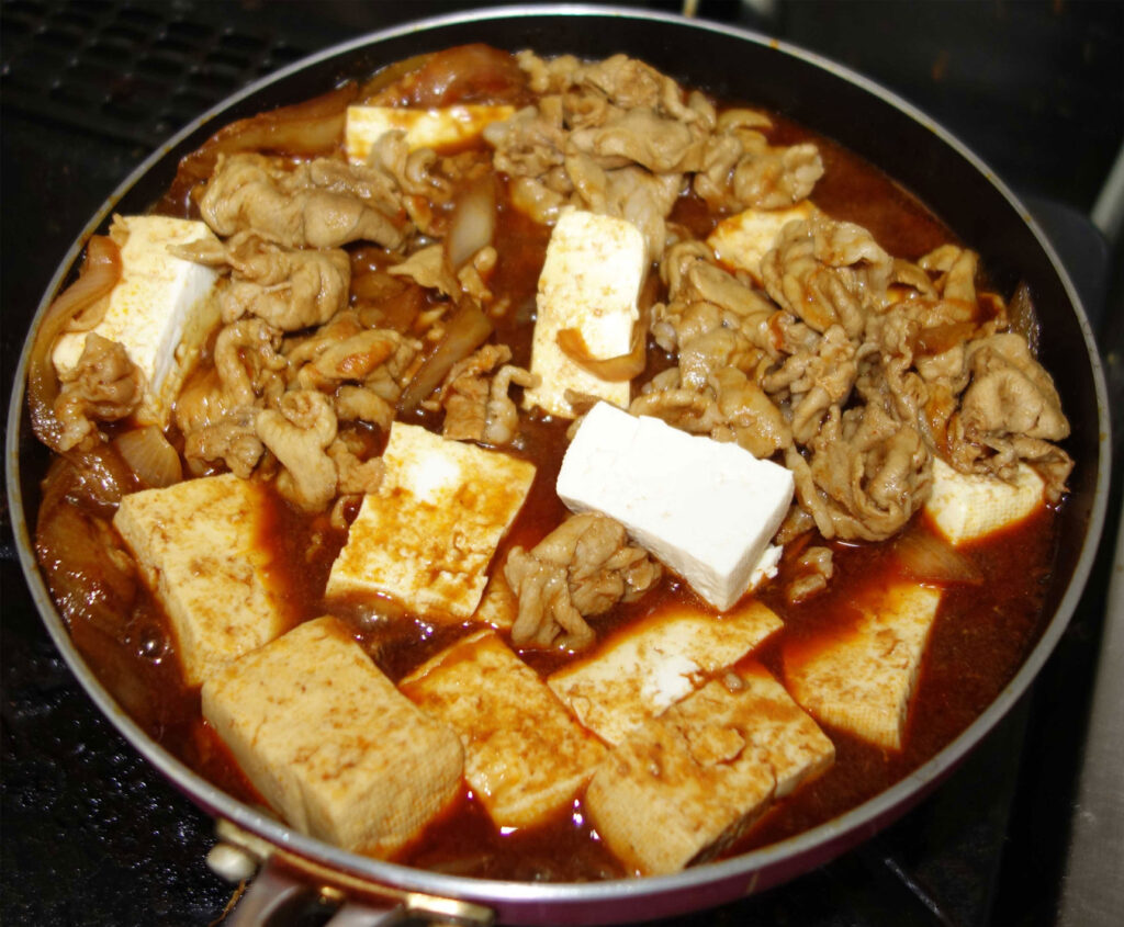 すき焼き鍋に入った豆腐と豚肉