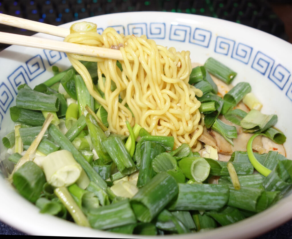 ネギたっぷりのラーメンを箸で持ち上げている様子