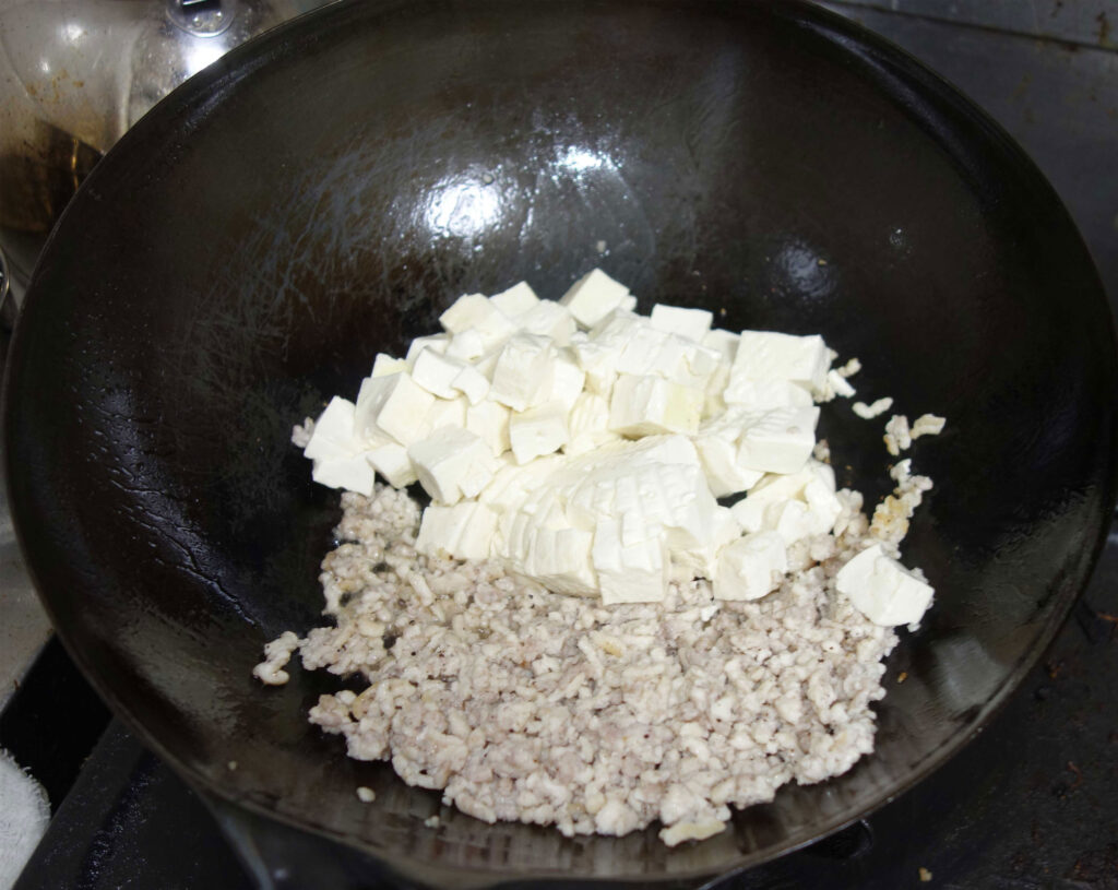 中華鍋で豆腐とひき肉を炒めている様子